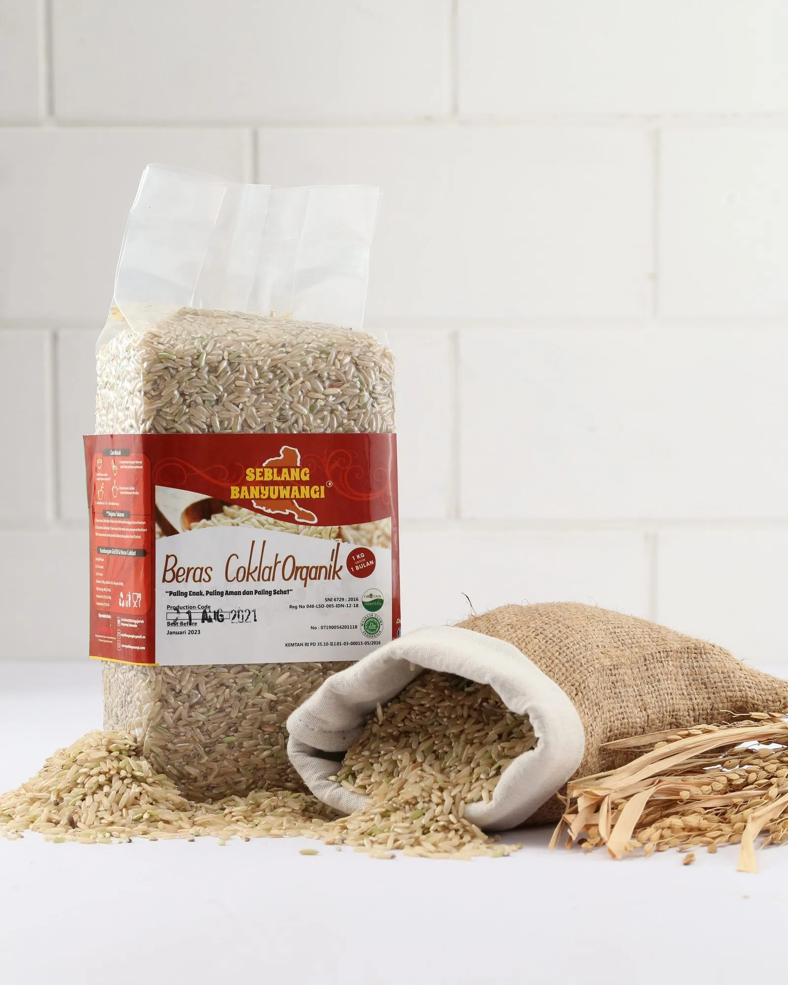 A one-kilogram pack of Sirtanio organic brown rice standing beside a jute sack of spilled brown rice