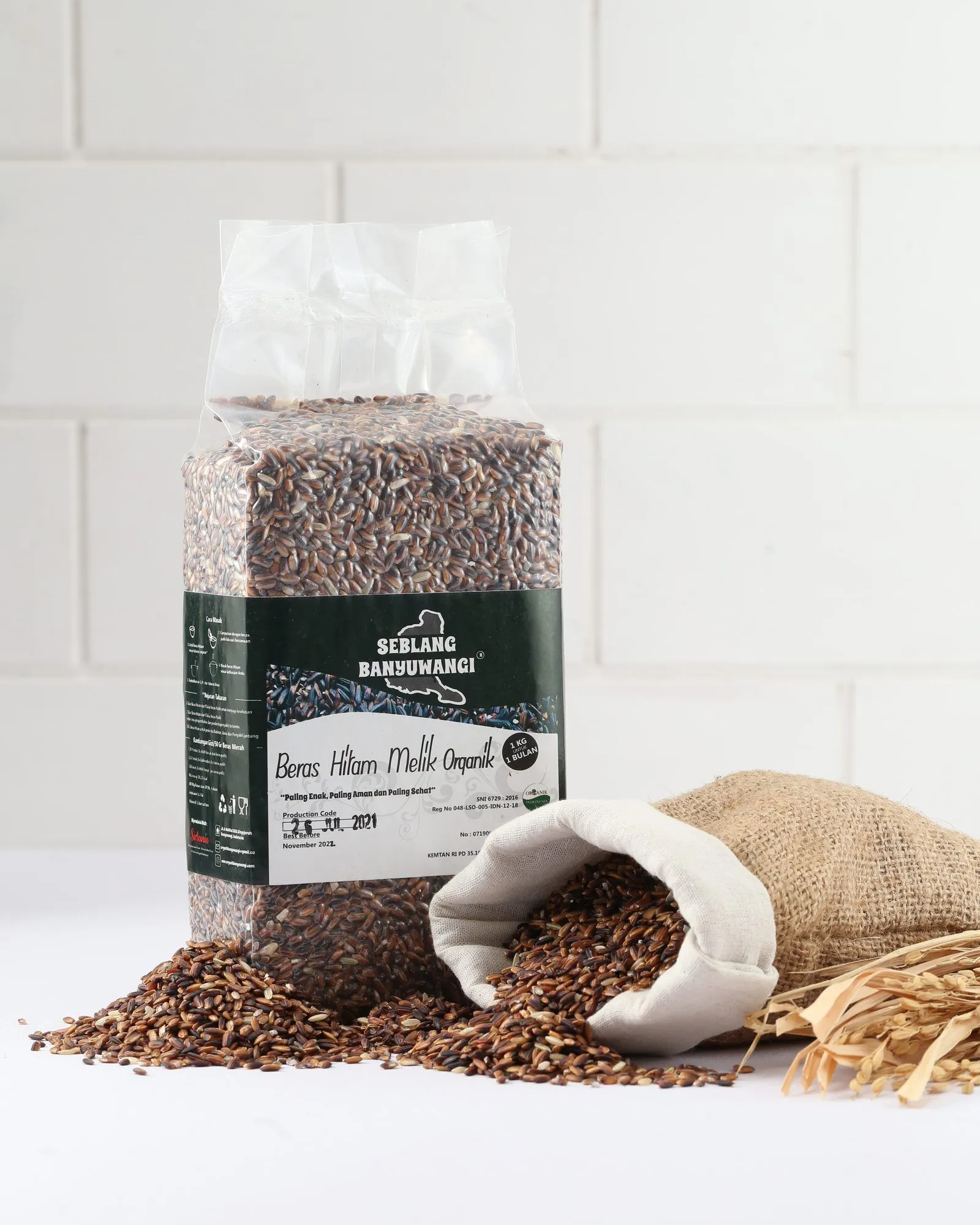 A one-kilogram pack of Sirtanio organic melik black rice standing beside a jute sack of spilled melik rice