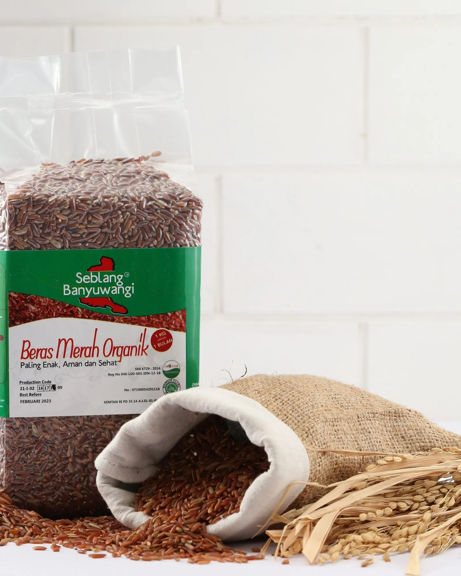 A one-kilogram pack of Sirtanio organic red rice standing beside a jute sack of spilled red rice