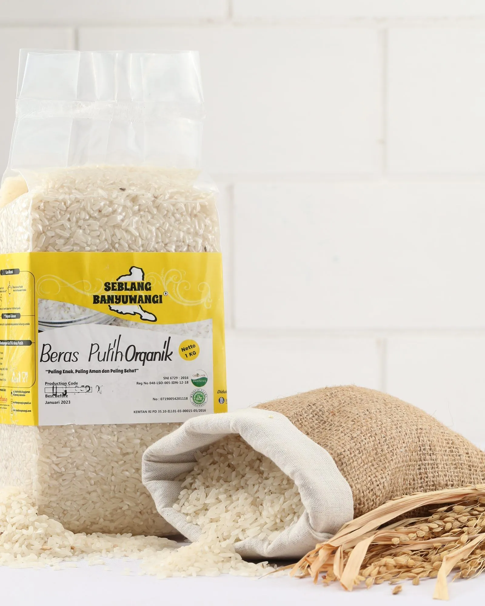 A one-kilogram pack of Sirtanio organic white rice standing beside a jute sack of spilled white rice